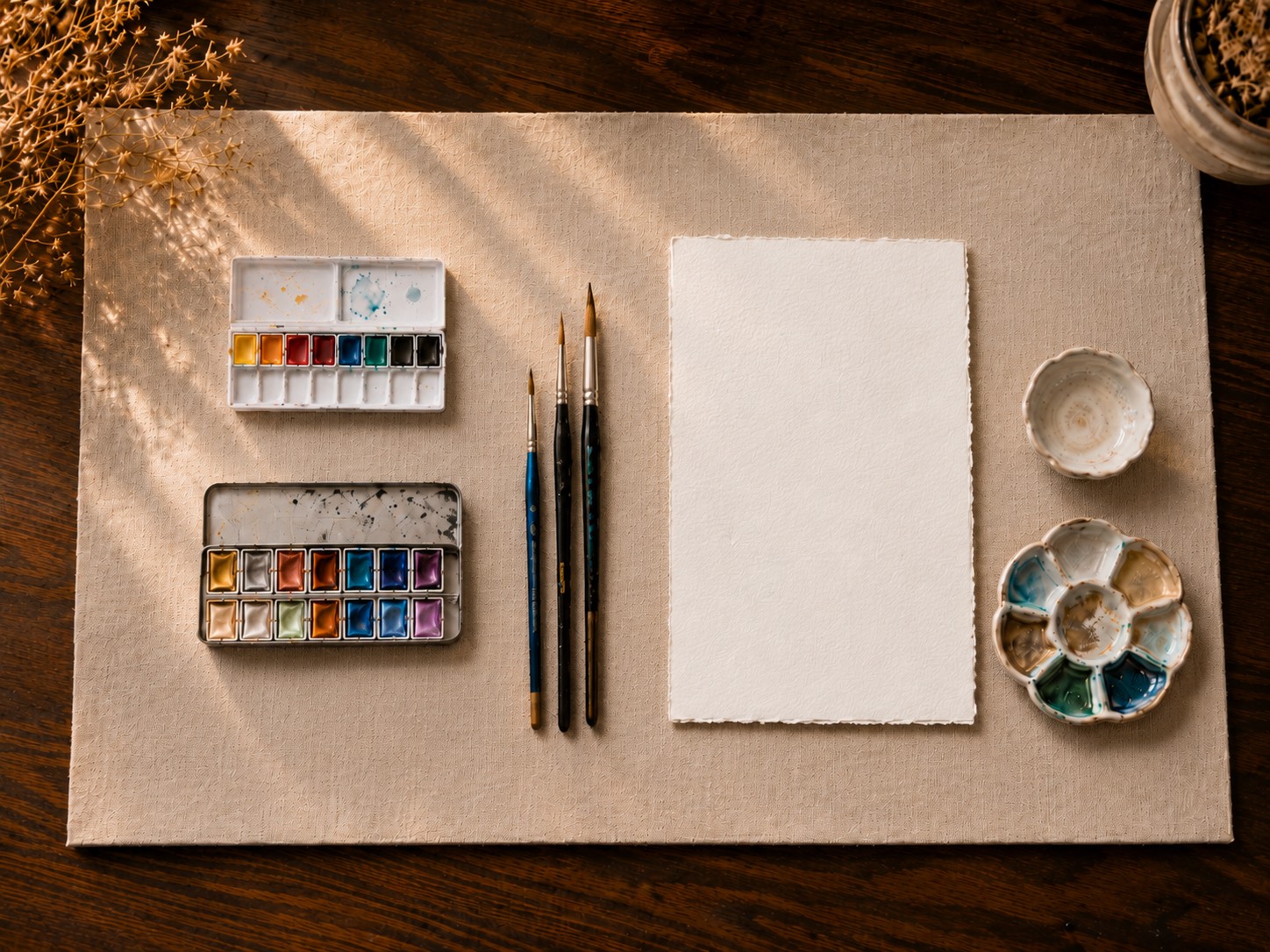 Flat-lay of the recommended watercolor paints, brushes, paper, and metallics